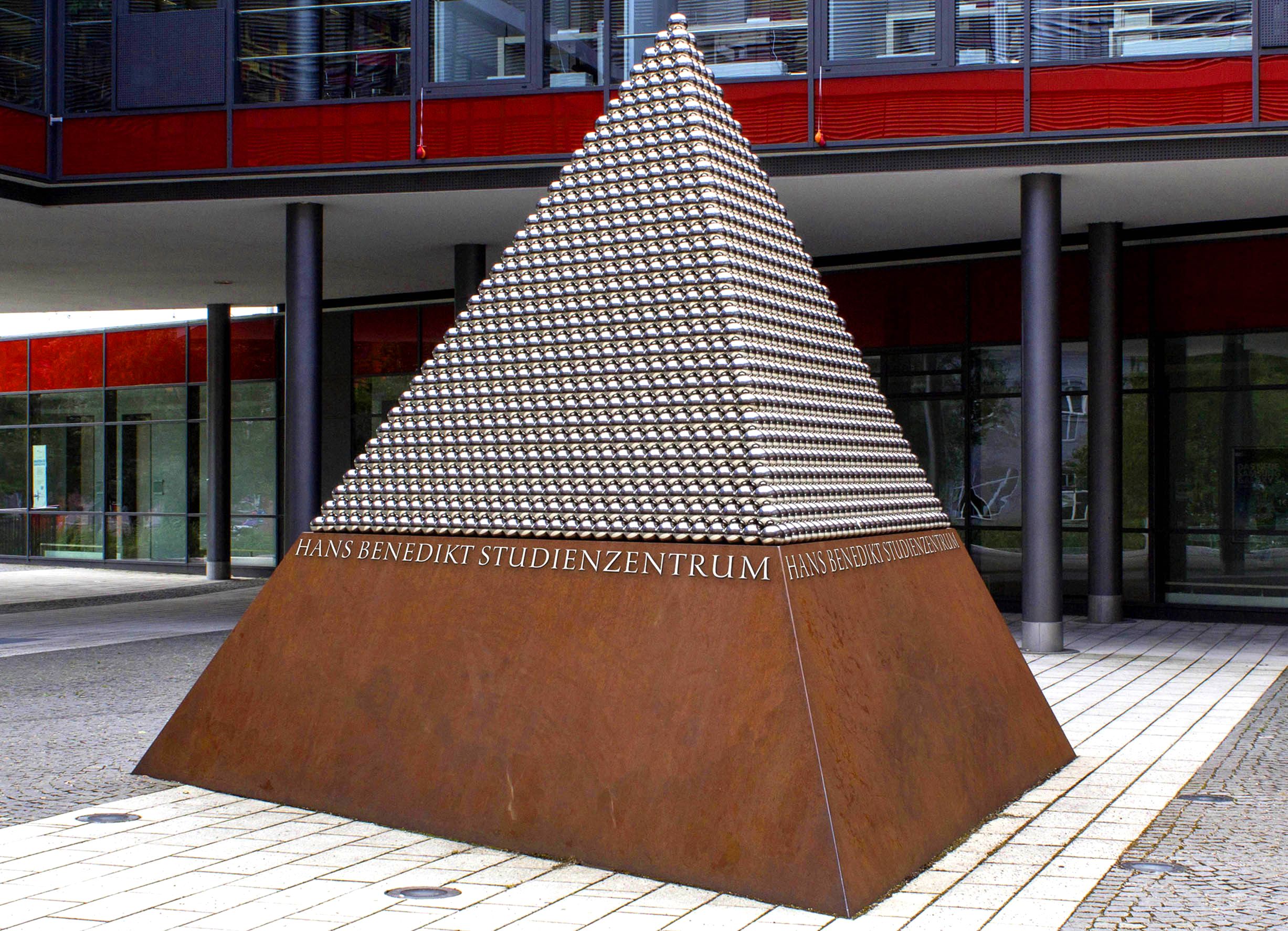 Art piece (pyramid shape) on the campus of Hochschule Augsburg featuring custom stainless steel lettering by Hans R. Heitmann